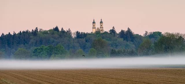 Panorama über Feld mit dem Kloster im Nebel